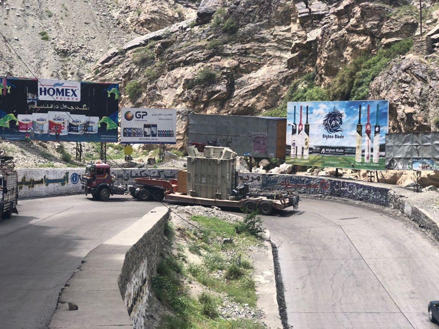 Power transformer secured on a multi-axle low-bed trailer during escorted inland transit through mountain terrain
